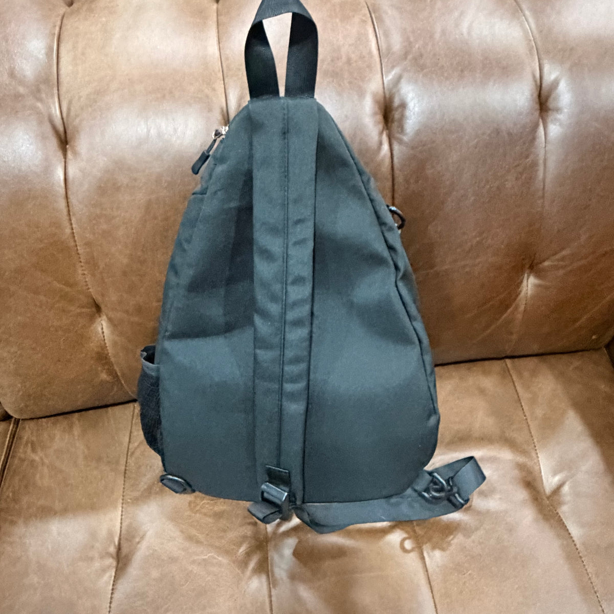 Back view of black KOMILO crossbody sling bag showing padded strap and back panel