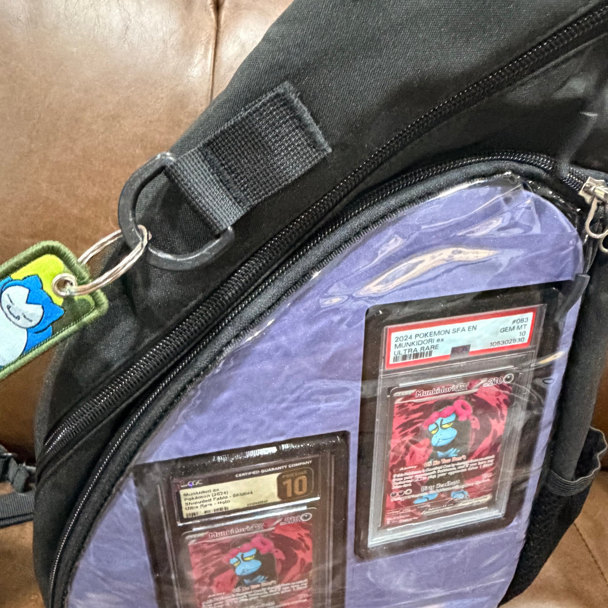 Black crossbody bag front view with light blue insert and Snorlax keychain