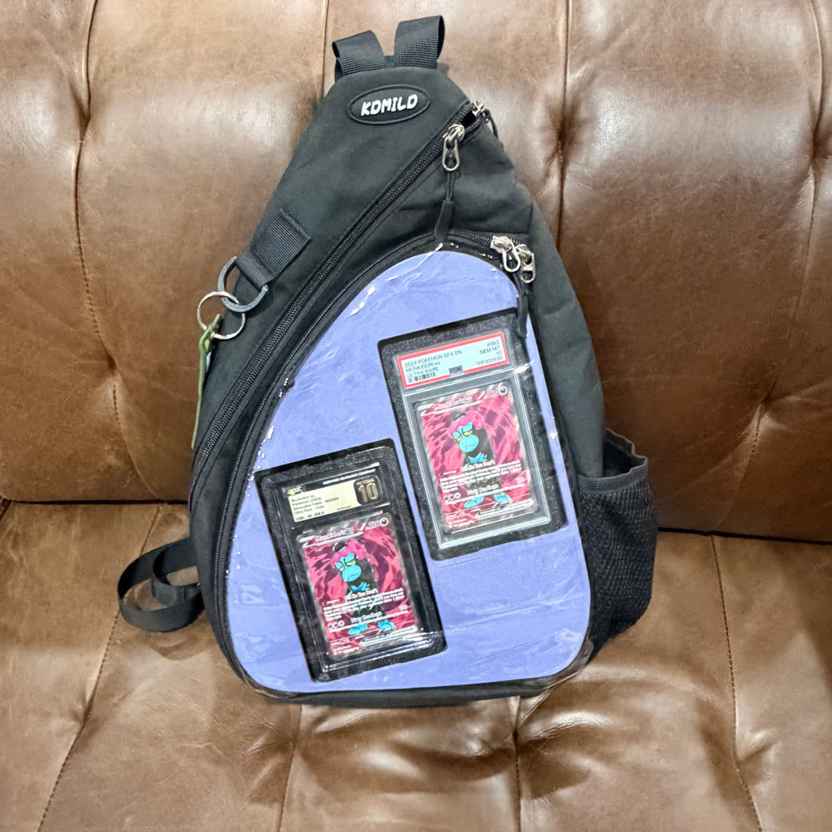 Black crossbody bag front with light blue insert showing graded Munkidori PSA and CGC slabs