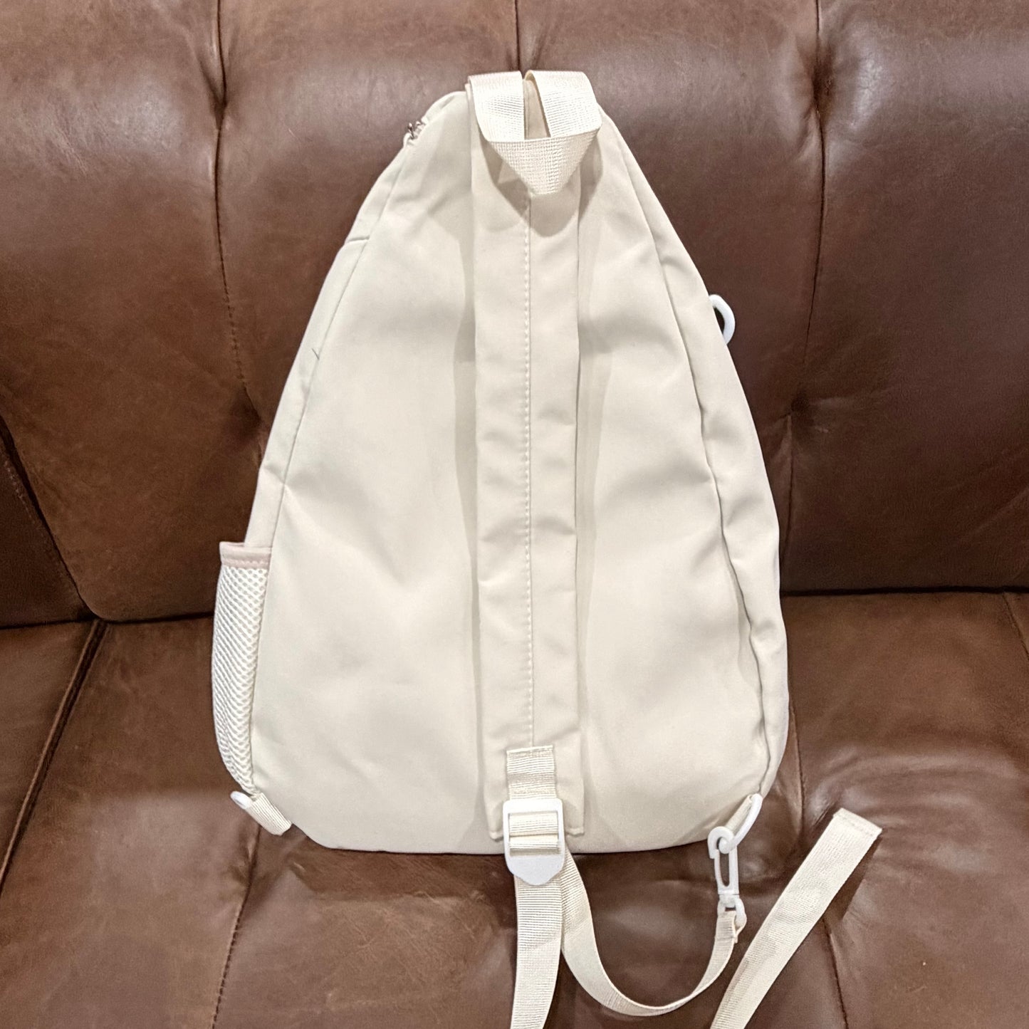 Back view of cream KOMILO crossbody sling bag showing padded back panel and adjustable strap