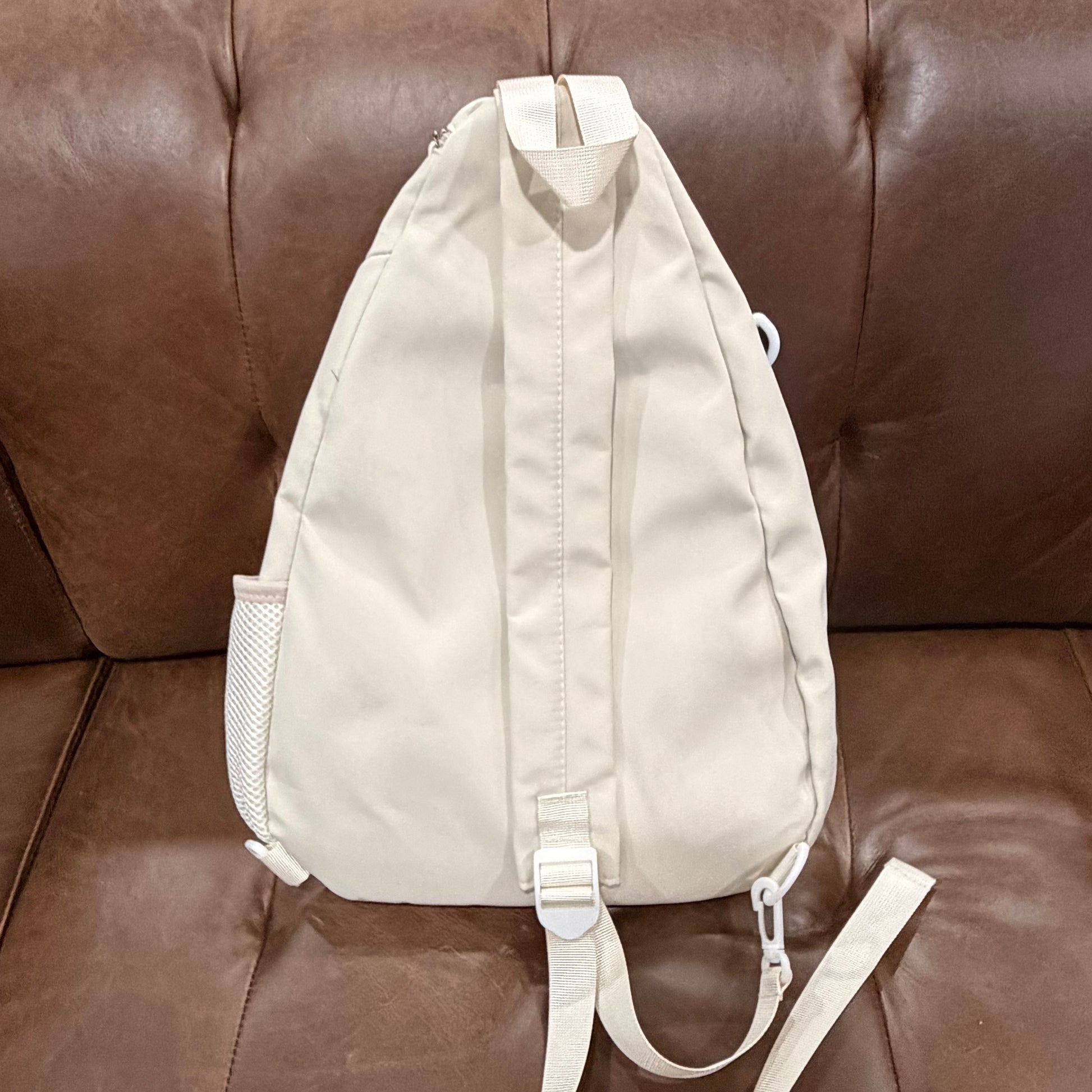Back view of cream KOMILO crossbody sling bag showing padded back panel and adjustable strap