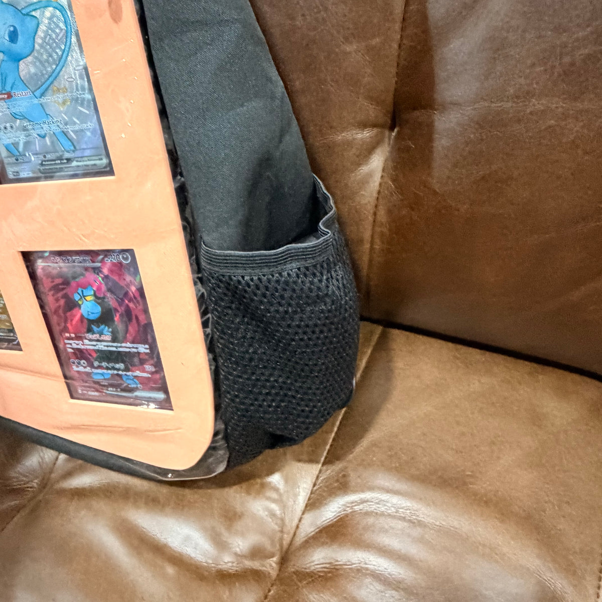 Side view showing mesh pocket on black crossbody bag with peach insert