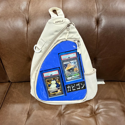 Cream KOMILO crossbody bag front with navy blue insert showing PSA graded Snorlax slabs and Kabigon nameplate