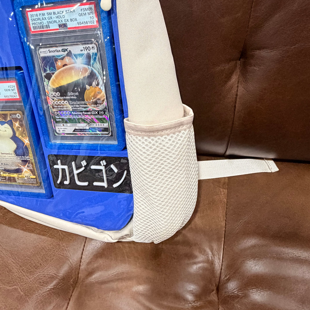 Close-up of cream KOMILO bag mesh side pocket with graded cards and nameplate visible